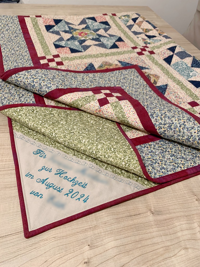 Das Bild zeigt den fertigen Quilt mit einer persönlichen Stickerei.